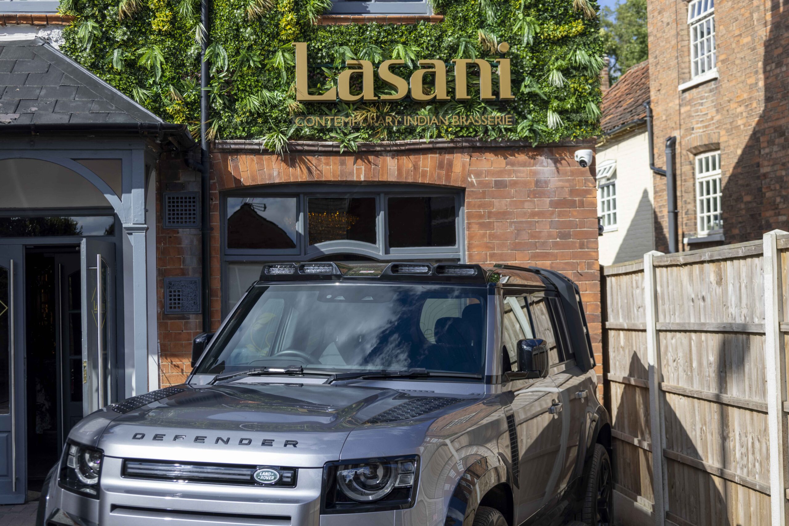 Land Rover Defender parked in front of Lasani Entrance and living wall sign.