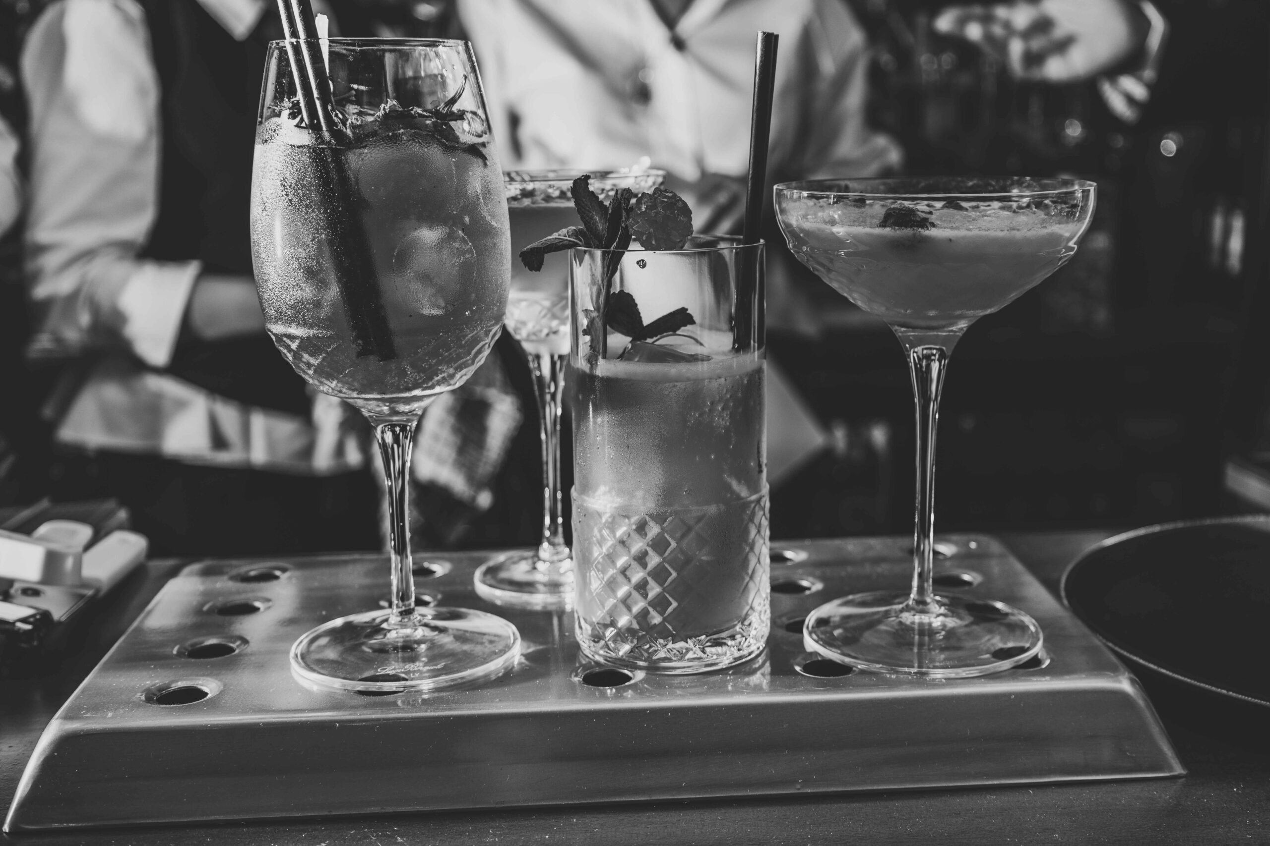 Greyscale image of a selection of brightly coloured cocktails